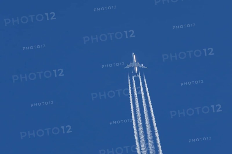 Airbus A340-300 jet aircraft of Lufthansa airlines in flight in a blue sky with vapour trails or contrails behind, England, United Kingdom