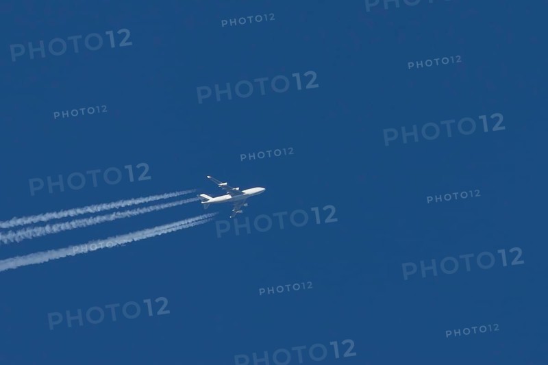 Boeing 747 Jumbo jet passenger aircraft in flight in a blue sky with vapour trails or contrails behind, England, United Kingdom