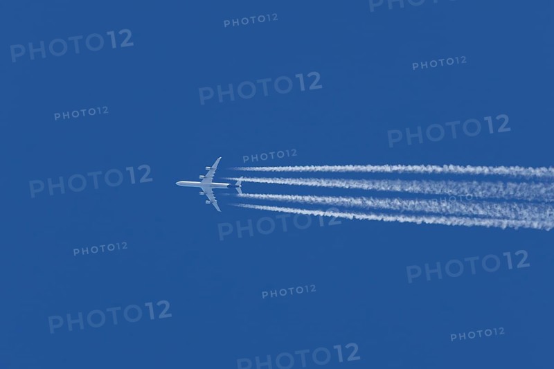 Airbus A340-300 jet aircraft of Lufthansa airlines in flight in a blue sky with vapour trails or contrails behind, England, United Kingdom