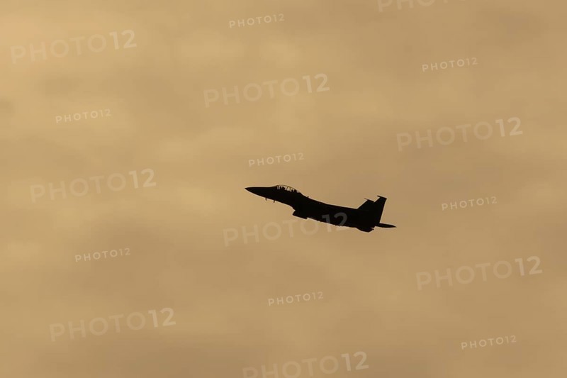 McDonnell Douglas F-15E Strike Eagle fighter military aircraft of the United States air force USAF in flight silhouette at sunset at RAF Lakenheath airbase, Suffolk, England, United Kingdom