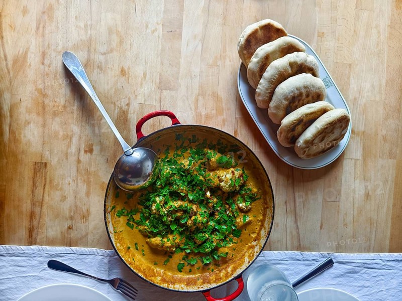 A pot of curry and herbs served with bread on a wooden table Lower Austria Austria