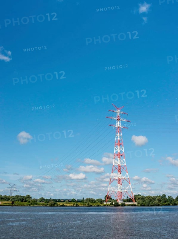 An extremely high electricity electricity electricity pylon, marked white and red, stands on the banks of the Elbe, river bank, Elbe crossing 2, 227 m high, highest overhead line pylon in Europe, surrounded by green landscape with trees and meadows under a blue sky, high-voltage pylon, overhead line pylon, overhead line, colour marking, safety, aviation safety, technology, structure, near Hollern-Twielenfleth, Lühe, Altes Land, Lower Saxony, Germany