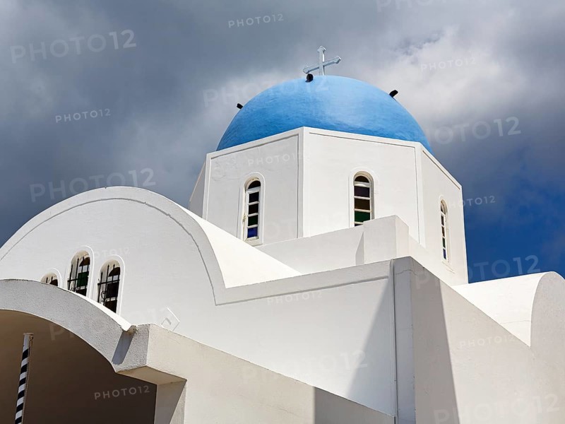 Orthodox church with blue dome, dramatic cloudy sky, Firostefani, Thira, Santorini, Cyclades, Greece