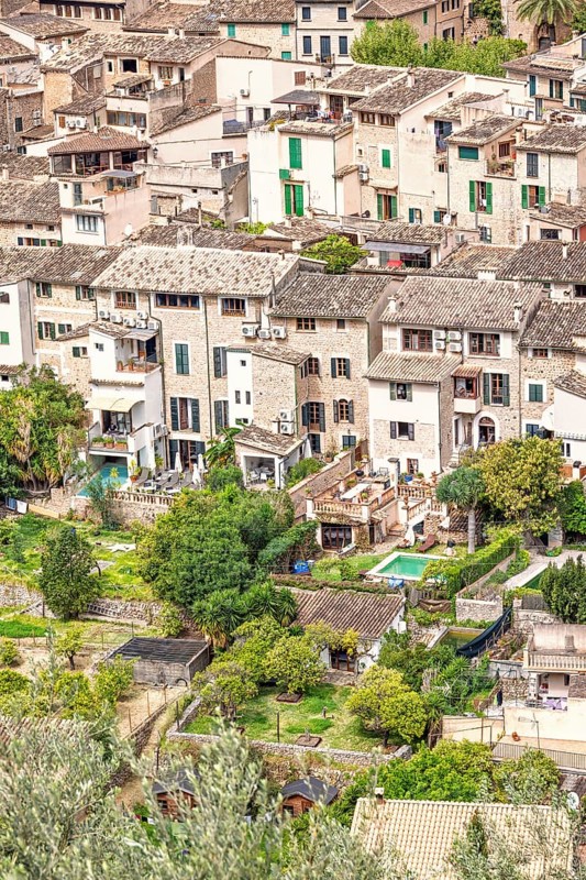 Aerial view at an old village with residential houses and gardens with lush trees in the summer, Fornalutx, Mallorca, Spain