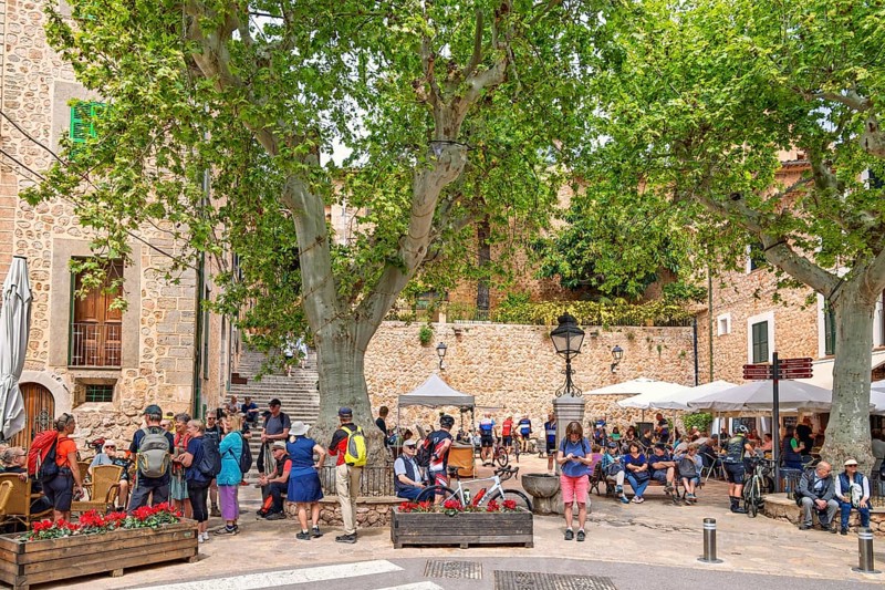 Many tourists in the square with outdoor restaurants in Fornalutx an old idyllic village in Mallorca, Fornalutx, Mallorca, Spain