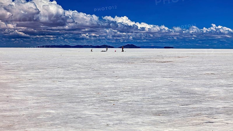Vast salt desert with small animal-like creatures and clouds in the blue sky, The endless expanses of the salt plain of the Salar de Uyuni in Bolivia