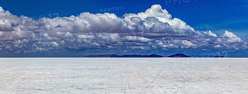 Wide cloud formation over a vast salt flat with distant mountain ranges, The endless expanses of the salt plain of the Salar de Uyuni in Bolivia