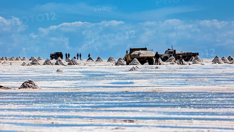 Vehicles and people move between salt hills on a shiny salt surface, The endless expanses of the salt plain of the Salar de Uyuni in Bolivia