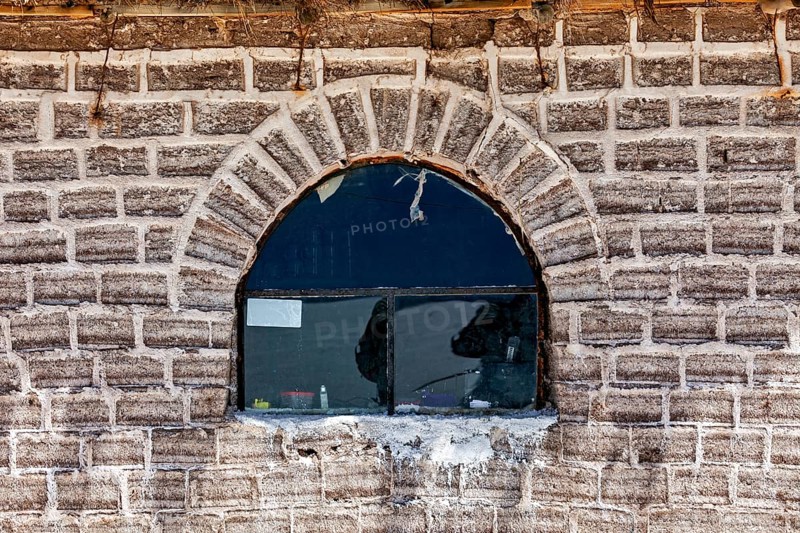The rustic window with reflection is located in a curved brick wall, A wall made of salt bricks in the Salar de Uyuni in Bolivia