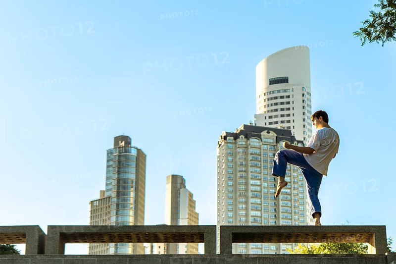 Young martial artist practicing a Taekwondo kick in the city