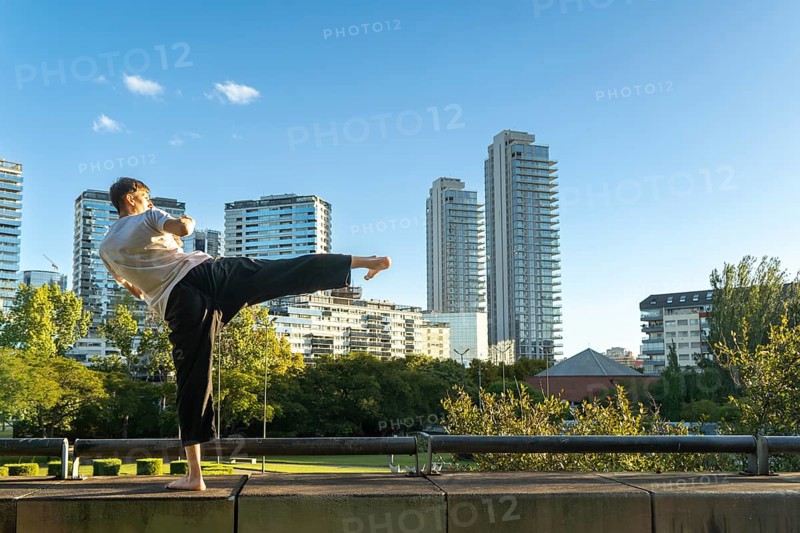 A focused Taekwondo practitioner against a modern city skyline