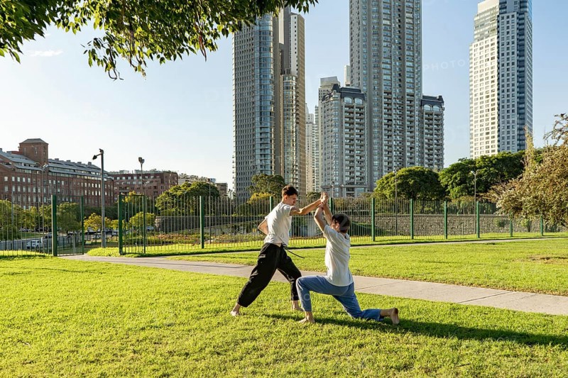Two young men sparring in a park on a sunny day
