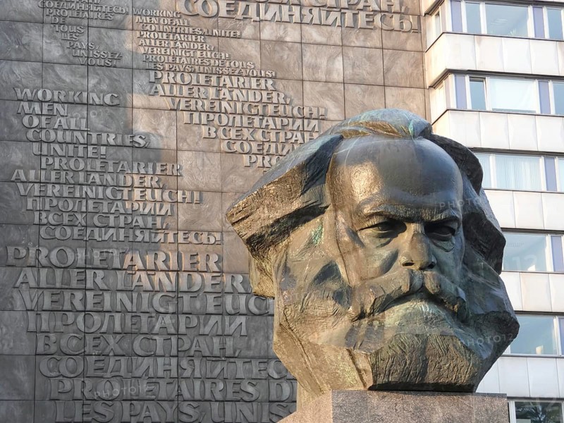 Stone bust of Karl Marx in front of a building with multilingual communist writings, Karl Marx monument in the city centre of Chemnitz, Saxony
