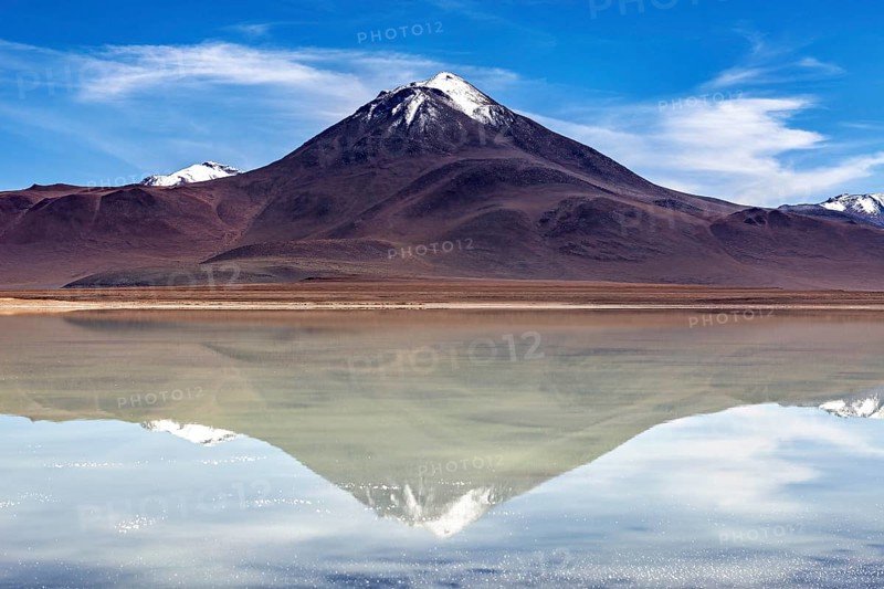 Majestic volcano reflected in a calm lake under a radiant sky, The Laguna Colorada in Bolivia
