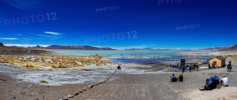 Panorama with sweeping views over a lake and mountains in an arid desert landscape, The Aguas Termales de Polques in Bolivia