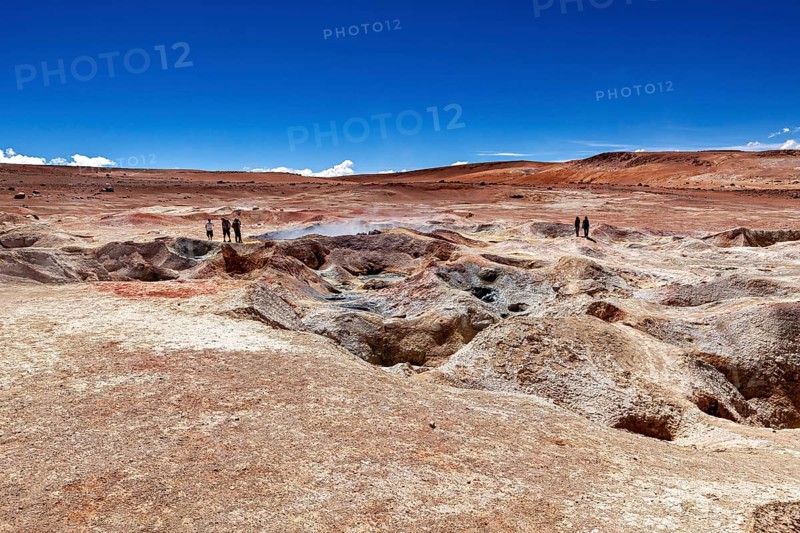 A glistening sky over vast desert plains with geysers and people in the distance, The mud volcanoes and fumaroles on the Altiplano in Bolivia
