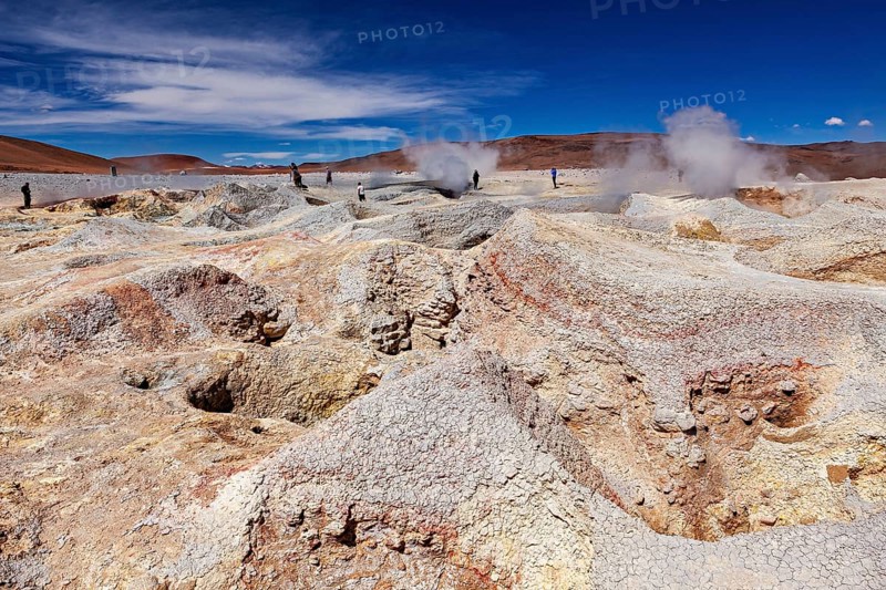 Steam rises from craters in a vast geothermal desert landscape, the mud volcanoes and fumaroles on the Altiplano in Bolivia