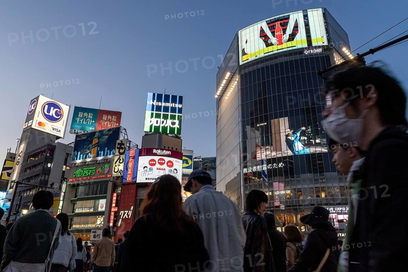 Crowd crossing the zebra crossings of Shibuya Crossing, world-famous intersection in Shibuya district, behind it neon signs and billboards on skyscrapers at dusk, tourist attraction, landmark, Shibuya district, Tokyo, Japan