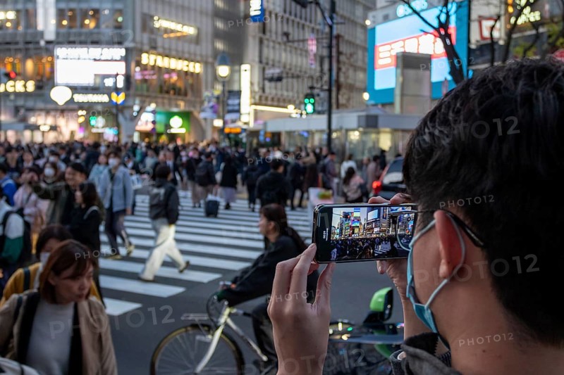 A tourist films the crowd at the zebra crossing of Shibuya Crossing with his smartphone, world-famous crossing in the Shibuya district, tourist attraction, sight, Shibuya district, Tokyo, Japan