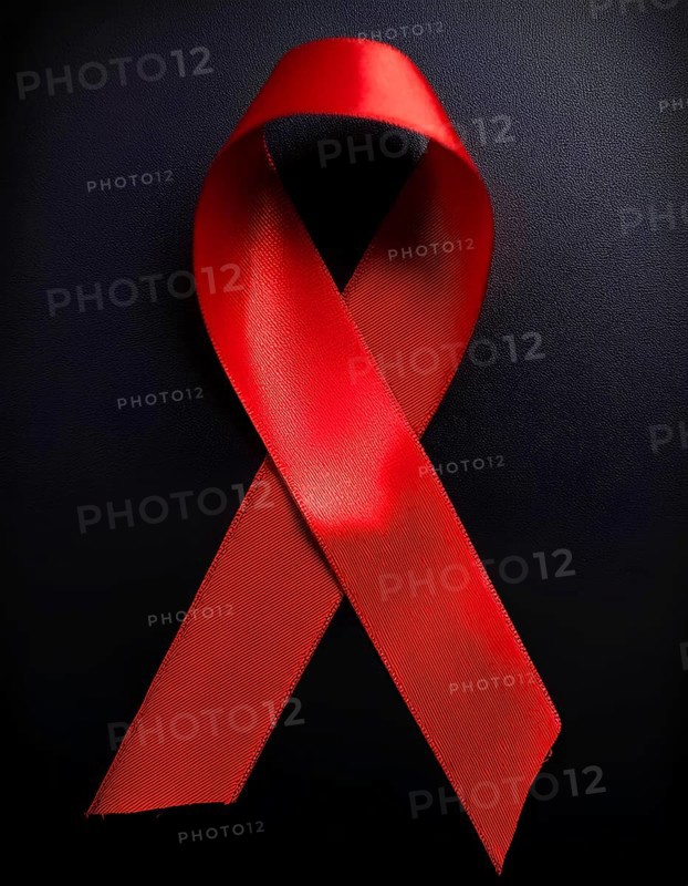 Close-up of a red awareness ribbon symbolizing support for causes like HIV/AIDS and heart disease, displayed against a black background, AI generated