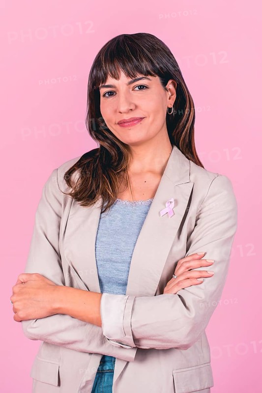 Positive woman with hands behind head and pink ribbon symbolizing breast cancer awareness