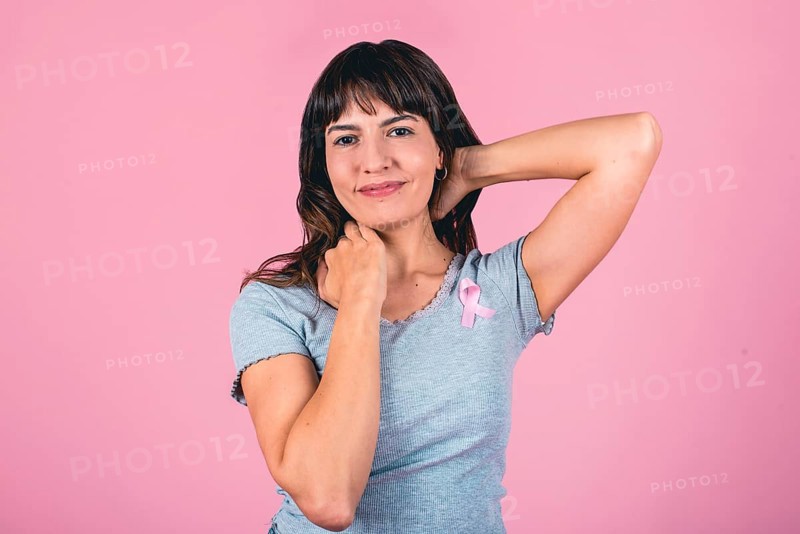 Smiling woman with pink ribbon raising awareness for breast cancer