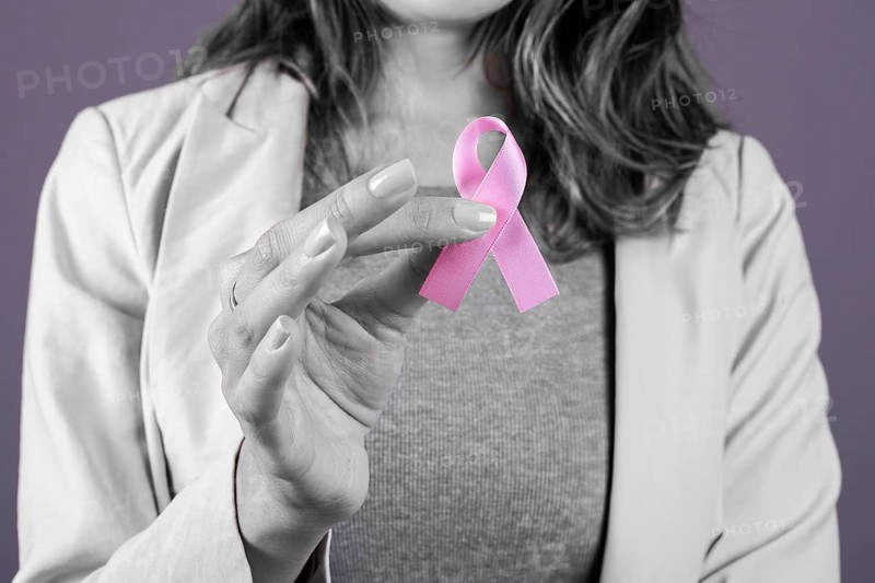 Woman holding a pink breast cancer ribbon, selective color on ribbon only