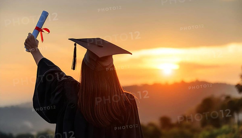 A graduate wearing a cap and gown raises a diploma with a red ribbon while standing outdoors at sunset, symbolizing achievement and new beginnings, AI generated