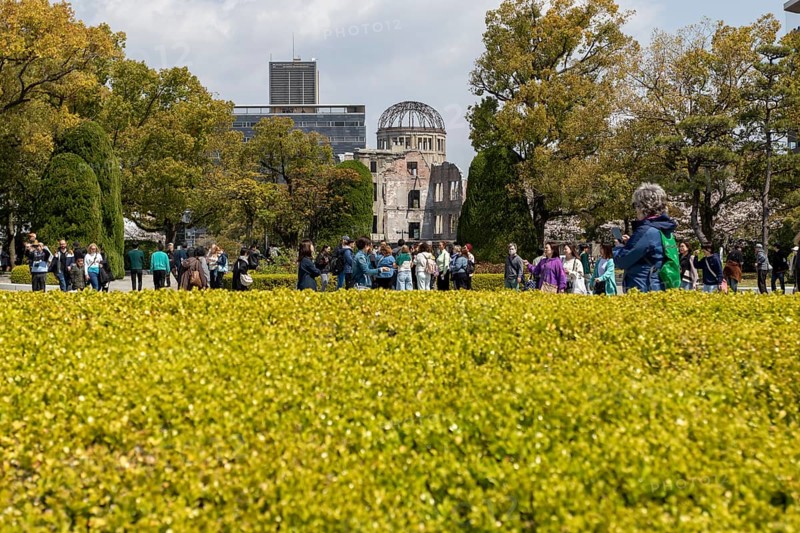 Tourists in the Peace Park with a view of the ruins of the Atomic Bomb Dome, landmark, UNESCO World Heritage Site, peace memorial and memorial to the victims of the atomic bombing of Hiroshima, Naka Ward, Hiroshima, Japan