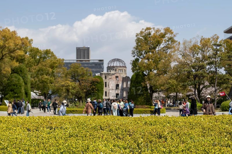 Tourists in the Peace Park with a view of the ruins of the Atomic Bomb Dome, landmark, UNESCO World Heritage Site, peace memorial and memorial to the victims of the atomic bombing of Hiroshima, Naka Ward, Hiroshima, Japan