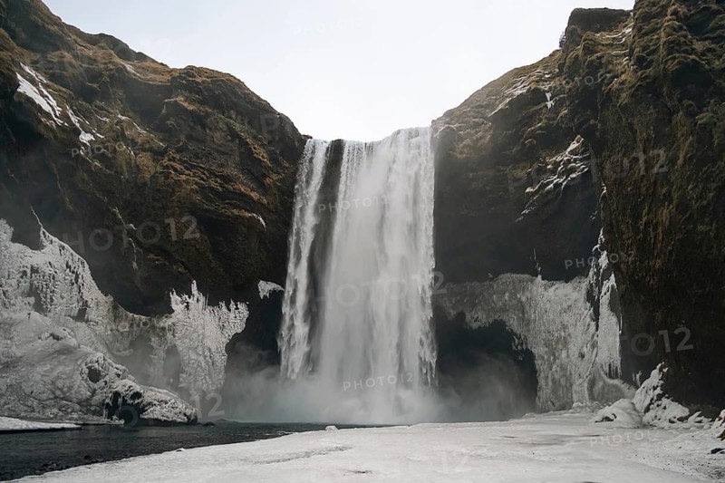 The mighty Skogafoss waterfall in winter. Roaring masses of water meet ice and rock. Skogar, Rangarping eystra, Iceland