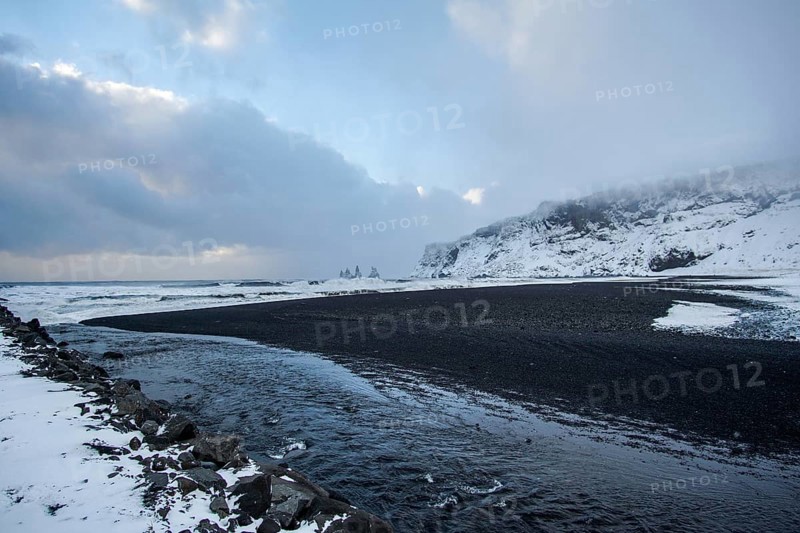 A black beach cuts through white stilts. A coastline like a painting. Renisfjara, Iceland
