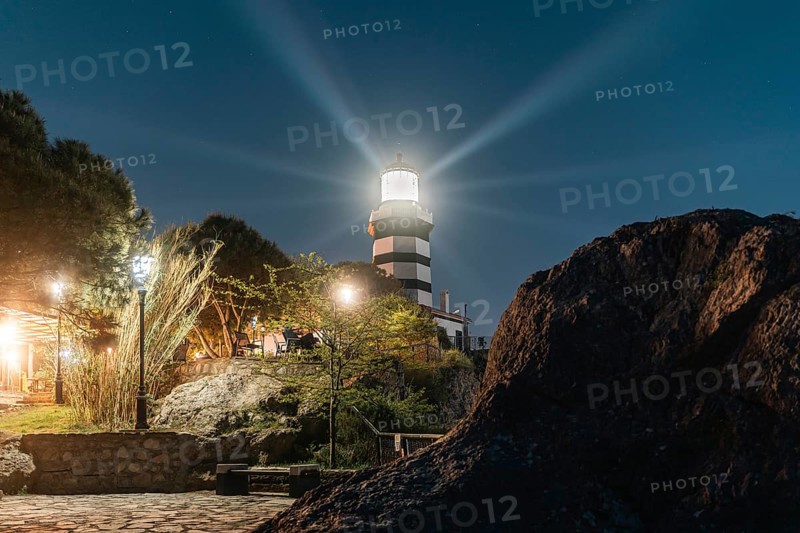 The Sile lighthouse at night. Radiant light over rocks and pine trees. Sile, Istanbul, Turkey