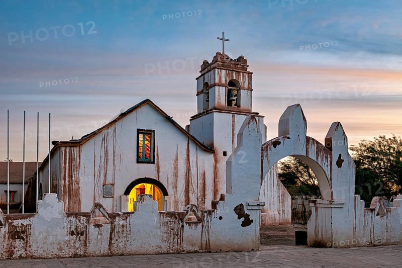 Illuminated church in the evening with warm light and ecclesiastical cross, The church of San Pedro de Atacama in Chile