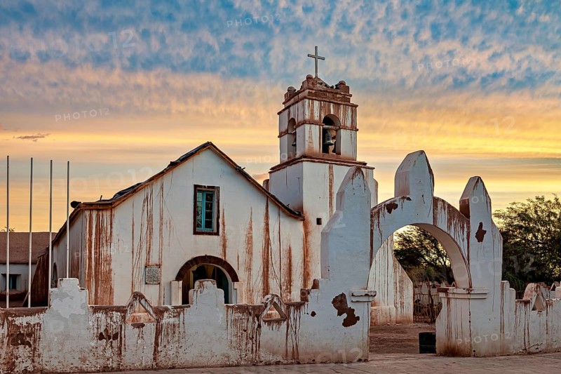 Church at dusk with warm colours and a striking church cross in the foreground, The church of San Pedro de Atacama in Chile