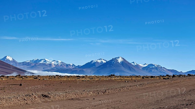 Vast dry desert landscape with snow-capped mountains and clear blue sky, The landscape at San Pedro de Atacama in Chile