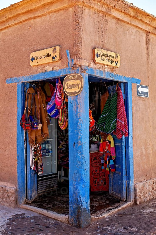Corner of a souvenir shop with colourful textiles and handicrafts. Rustic style with striking blue door frame, The market with souvenir shops in San Pedro de Atacama in Chile