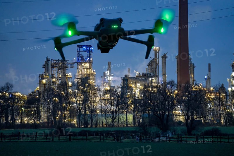 Symbolic image, photomontage, reconnaissance, spying with drones in industrial plants, critical infrastructure, drone flies towards an industrial complex, chemical plant, spying by camera drones