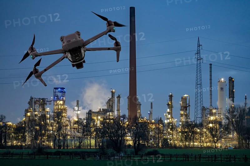 Symbolic image, photomontage, reconnaissance, spying with drones in industrial plants, critical infrastructure, drone flies towards an industrial complex, chemical plant, spying by camera drones