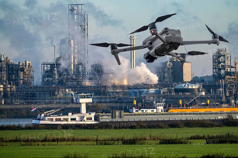 Symbolic image, photomontage, reconnaissance, spying with drones in industrial plants, critical infrastructure, drone flies towards an industrial complex, chemical plant, spying by camera drones