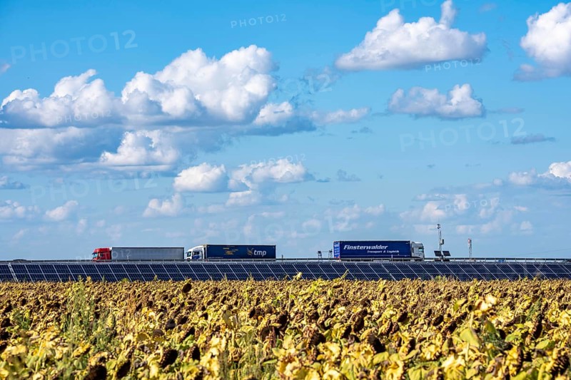 86, 5 MW peak ground-mounted photovoltaic systems, by RWE, with over 141, 000 solar modules, on a verge, over 1 km long, along the A44 motorway near Bedburg, at the Jackerath junction, recultivated open-cast mining site, field with sunflowers, North Rhine-Westphalia, Germany