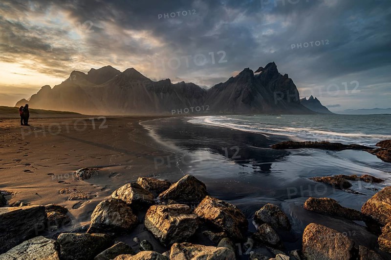 Two people standing on the beach, couple, adult, mountains, mountain range, sea, waves, surf, reflection, clouds, evening light, coast, summer, Vestrahorn, Stokksnes, Höfn, Iceland
