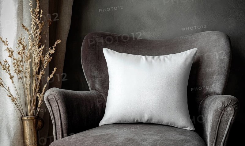 A white pillow sits on a gray chair in a room with a window. The pillow is placed on the back of the chair, and the chair is positioned in front of the window. The room has a cozy. AI generated
