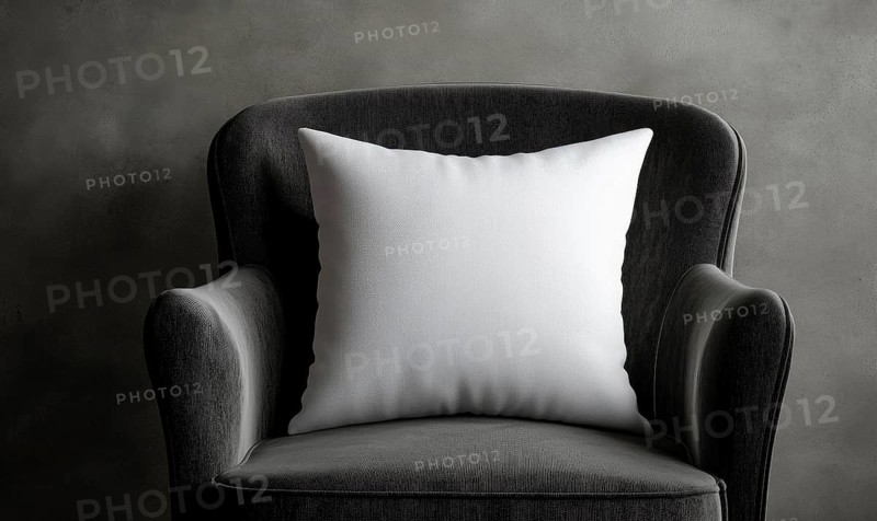 A white pillow sits on a black chair. The chair is made of wood and has a natural texture. The pillow is placed on the back of the chair, and the chair is positioned in front of a wall. AI generated