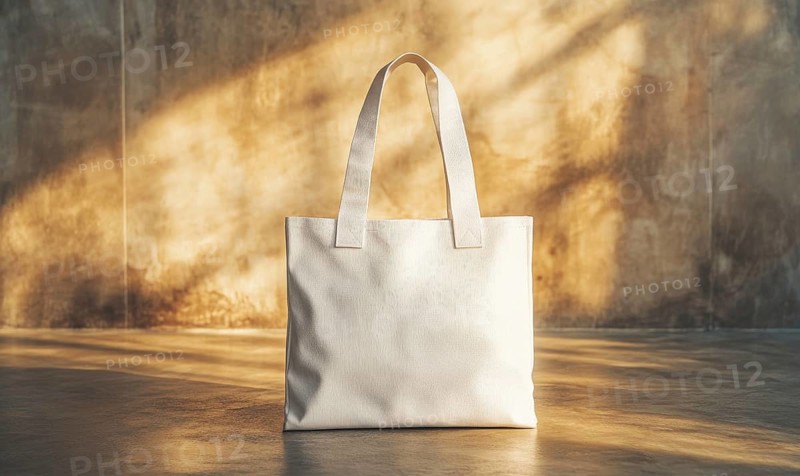 A white bag with a brown handle sits on a concrete floor. The bag is open and the handle is visible. The bag is placed in front of a wall, with the wall casting a shadow on the floor. AI generated