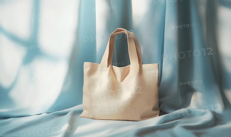 A tan purse is sitting on a blue cloth. The purse is made of leather and has a pattern on it. The cloth is blue and has a shiny texture. Concept of luxury and elegance. AI generated
