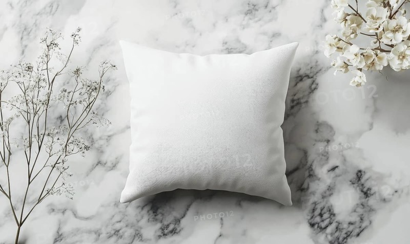 A soft white pillow on a marble surface with delicate flowers under gentle lighting. AI generated