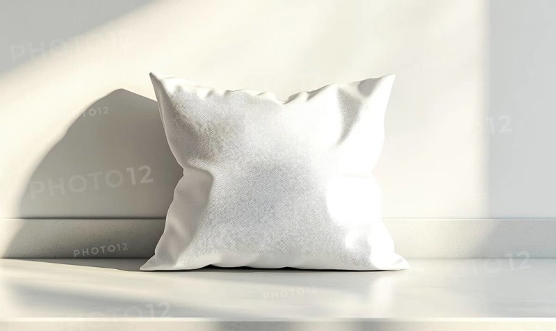 A white pillow sits on a countertop in a room with a window. The pillow is unmade and he is a decorative item. The room is bright and airy, with sunlight streaming in through the window. AI generated