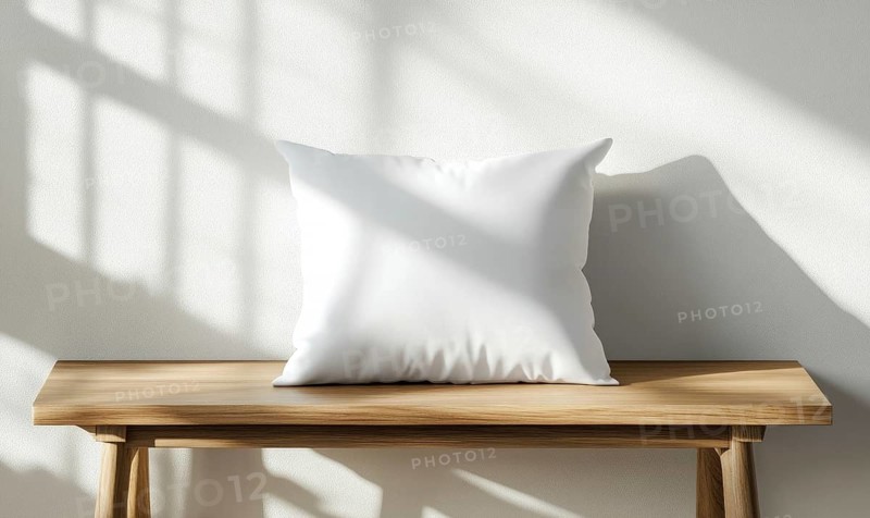 A white pillow sits on a wooden bench in front of a white wall. The pillow is empty and the bench is empty. The scene is simple and uncluttered, with the pillow. AI generated