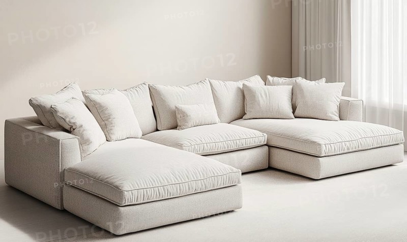 A spacious beige sectional sofa with plush pillows in a bright, cozy room. AI generated